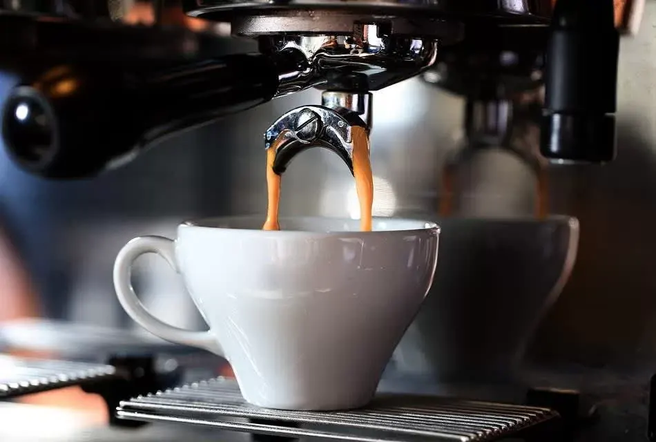 Espresso teče z páky kávovaru do bílého šálku
